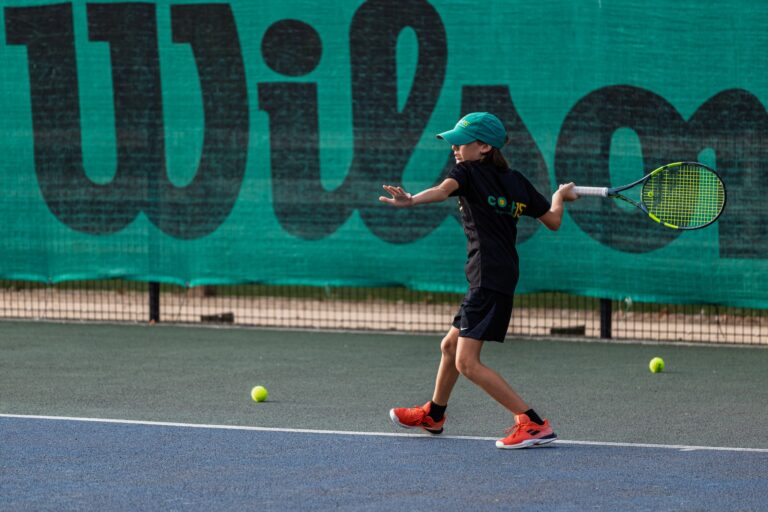 Junior tennis player preparing a forehand with a tennis racket on an outdoor court