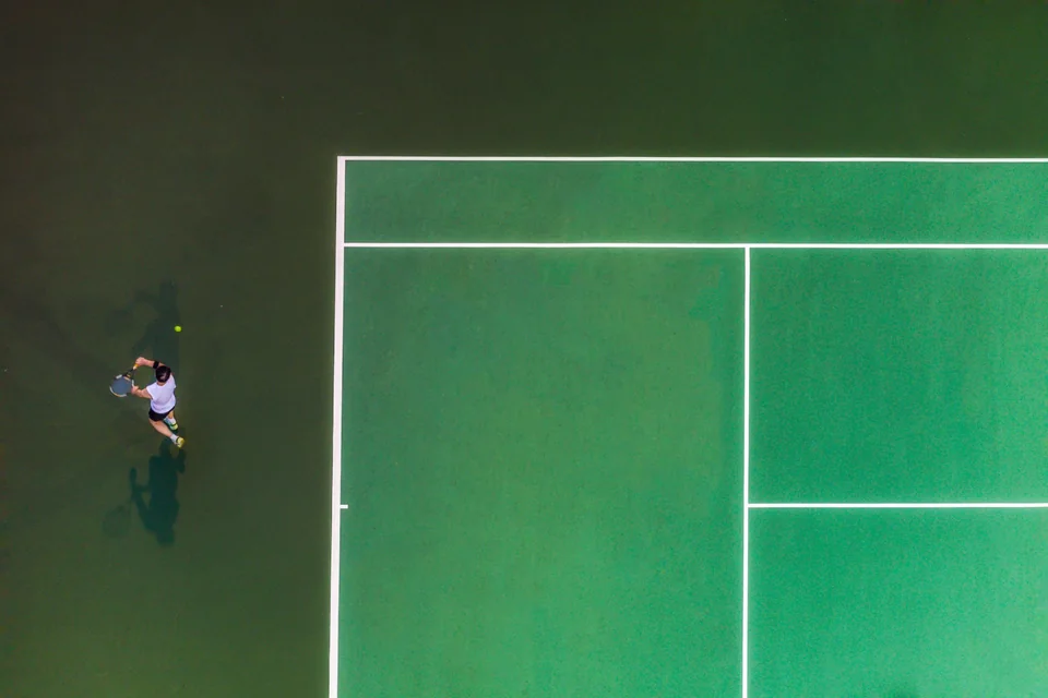 Overhead view of a tennis player on a green court
